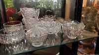 Showcase of all crystal bowls, frosted glass lidded candy dish, and crystal vase on glass shelf