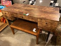 Image showing the full desk with faux wood top, metal legs, four drawers with black knobs, and a wooden bench underneath.