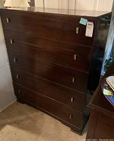 Front and angled views of dark wood dresser with five drawers and rectangular metal knobs, showing scratches and condition.