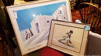 Two framed art pieces: a large Deborah Hyatt gallery poster and a smaller watercolor painting of a skier