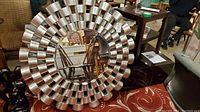 Front view of the round mirror showing the metallic enameled resin frame with cylindrical elements surrounding the beveled mirror center.