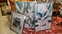 View showing two botanical canvas prints and a framed black and white photo of an old house.