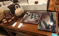 Overview photo showing the tea set cups, teapot, pitcher, vase, and two trays arranged on a wooden sideboard.