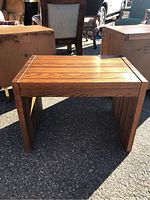 Front and side angle of the rectangular wood side table with faux wood grain finish, showing flat top and vertical side panels forming the structure.