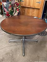 Full view of the solid walnut round table on metal base, showing wood surface and base structure.