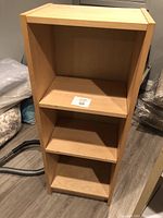 Front view of wooden bookshelf with four shelves and light wood finish.