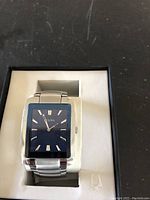 Front view of Bulova men's watch with blue square face in display box.