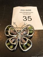 Top view of butterfly pin showing silver-tone metal and colored stones on wings