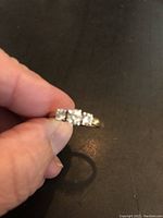 Frontal view of ring showing three round brilliant diamonds in prong setting on gold band