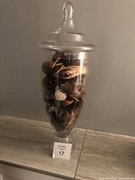 Lidded glass jar filled with dried potpourri placed on a wooden surface
