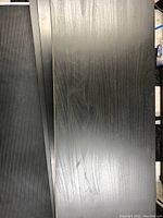 Top view of black wooden shelf showing wood grain and light surface scratches.