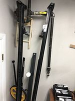 Metal frame parts for a bed, attached to a wall for display, showing long side rails with adjustment slots and center support beam.