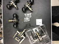 Photo showing three black round door knobs with silver internal mechanisms, mounting screws, and metal strike plates laid on black surface