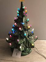 Front view of the ceramic Christmas tree lit up with multicolored lights.