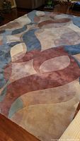 Full view of the Momeni wool hand tufted area rug with abstract patterns on hardwood floor