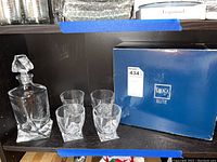 Mikasa Elite crystal square-base decanter with stopper, 4 high ball glasses arranged beside the original Mikasa Elite blue box.