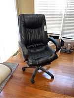 Front angle view of black leather office chair showing overall condition and structure with all casters visible except one