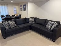 Front view of entire charcoal gray sectional queen sleeper sofa with nailhead trim and throw pillows