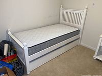 Side view of the entire twin trundle bed with white frame and mattress.