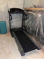 Full view of the treadmill set up in a basement location. Digital console and handrails visible. Flooring is concrete and surroundings include reflective insulation on the wall.
