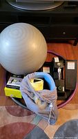The whole lot showing all items clustered together: silver exercise ball, purple weighted hula hoop, Cubii stepper, yellow kickboard, and mesh bag with gloves.