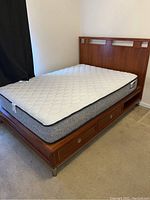 Full sized wooden captain's bed frame with mattress on top, showing headboard and four drawers beneath.