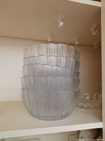 Five translucent glass bowls stacked together showing scalloped edges and vertical textured lines