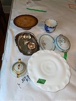 Photo of assorted ceramic dinnerware including white scalloped cake plate, floral bowls, Limoges sugar bowl, and small covered plates, along with a silver plated tray holding a creamer and sugar set.