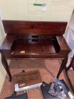 Wood desk with the top open showing interior drawers and damaged wood surface.