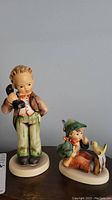 Full view of both Hummel figurines showing size difference and detailing