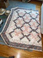 Full view of quilt laid flat on floor showing overall pattern and scalloped border