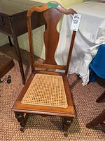 Front view showing carved wood backrest and cane seat