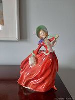 Full view of Royal Doulton "Autumn Breezes" figurine in flowing red dress, standing on tabletop.