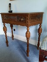 Front angle of wooden phone side table showing carved drawer front and legs with spindle design.