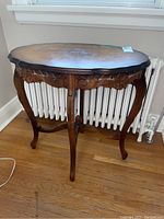 Front view of oval wooden table showing carved legs and detailed apron.