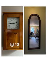 Photo of a narrow, long mirror with a dark wood frame featuring an arched top, reflecting a room inside.