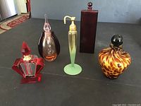 Five assorted perfume bottles displayed side by side on a dark surface showing size and design variation.