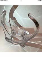 Single clear crystal centerpiece bowl with elegant curved extensions displayed on a light background casting reflections.