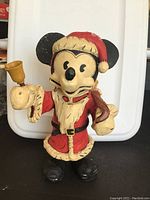 Front view of Mickey Mouse figurine in Santa suit holding bell.