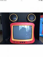 Front view of Disney Mickey Mouse TV with large black speaker ears, red and yellow frame around 13 inch screen, power cord visible on left side.