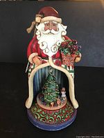 Full front view of Jim Shore Santa figurine, showing intricate paint and flower pot detail.