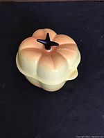 Top view of yellow bell pepper shaped cocotte with black stem handle on lid.