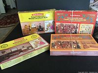 Four boxed Realife Miniatures dollhouse builder kits arranged on black surface, showing vintage box art and titles.