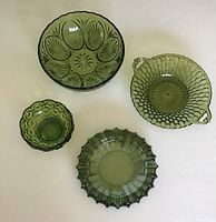 Top-down view of all four avocado green glass dishes showing various sizes and textures, arranged on a light surface.