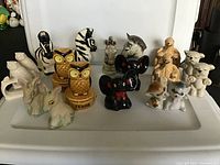 Front view of the complete lot showing various anthropomorphic animal salt and pepper shakers on a white surface.