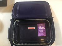 Top view of Pyrex covered glass dish inside the thermal bag, showing the blue lid with Pyrex branding and clear glass dish inside.