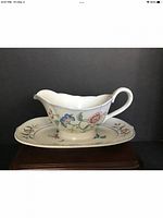Front view of gravy boat on matching underplate showing floral design and shape