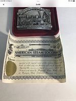 Close-up photo of the brass plaque in the velvet display case alongside the certificate of authenticity showing limited edition number 131/1000.