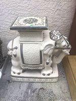 Side view of white ceramic elephant statue with gold decorative details, showing ornate saddle and chained leg decorations on a rectangular base.