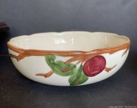 Side view of the Franciscan Apple ceramic serving bowl showing red apple and branch design with green leaves and scalloped brown rim.